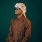 Stylish portrait of a man wearing traditional Middle Eastern clothing and sunglasses indoors.